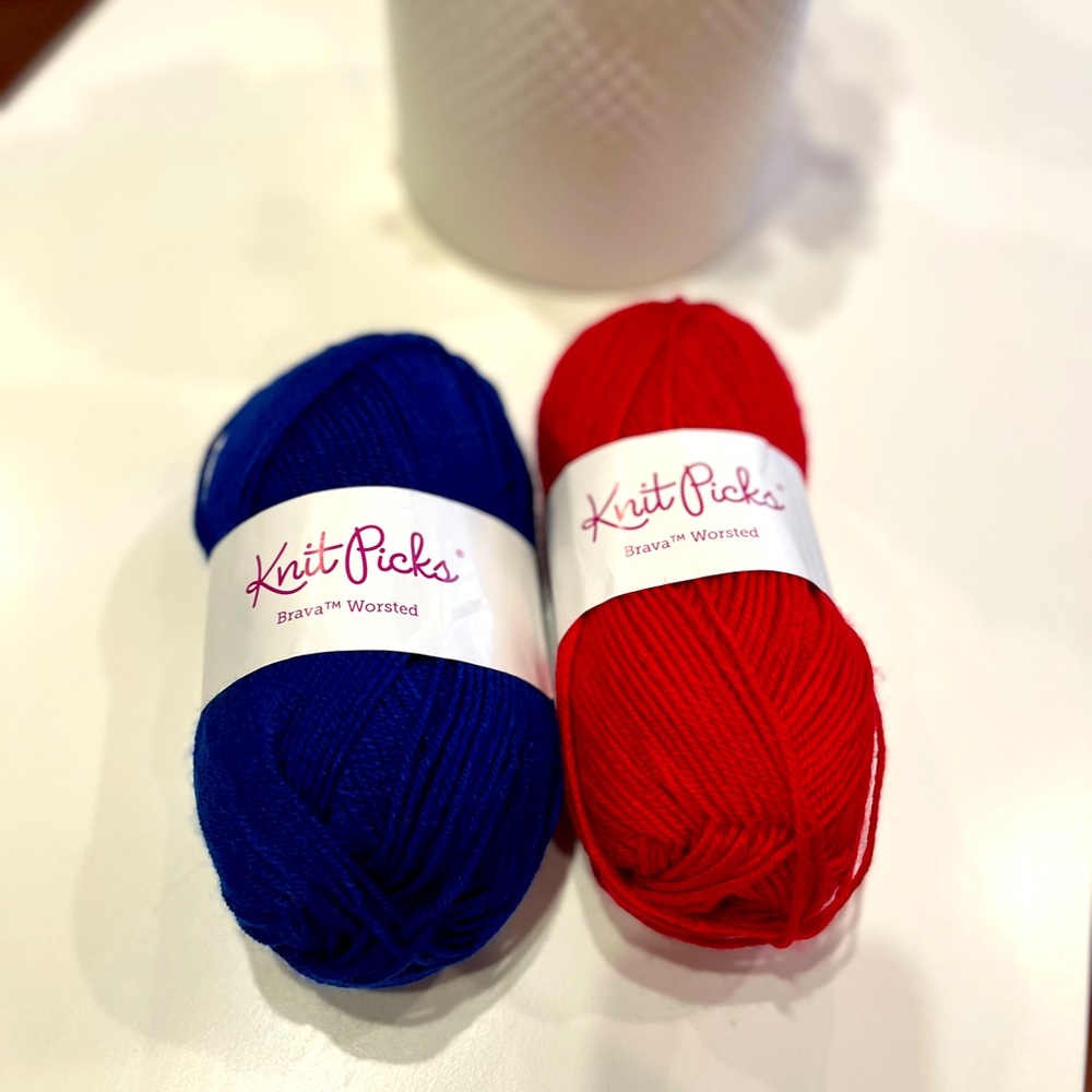 Two skeins, balls of knit picks Brava worsted weight yarn. Red and blue